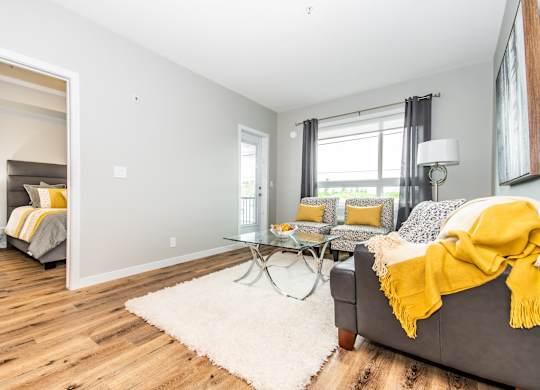 A bedroom with a grey couch and a yellow blanket.