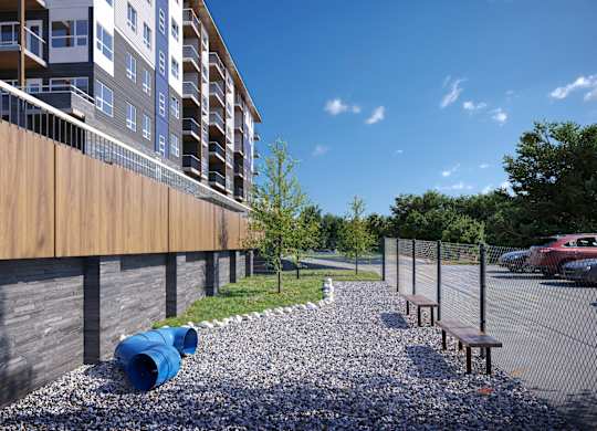 A modern building with a wooden fence and a gravel area with benches.