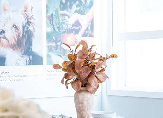 A dining table with a vase of flowers on it.