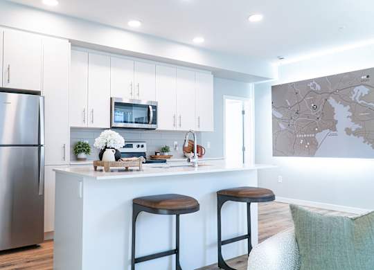 A modern kitchen with a bar stool and a fridge.