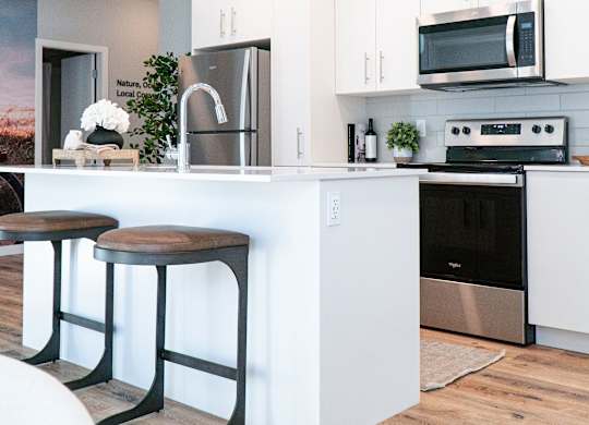 A modern kitchen with white cabinets and a wooden floor.