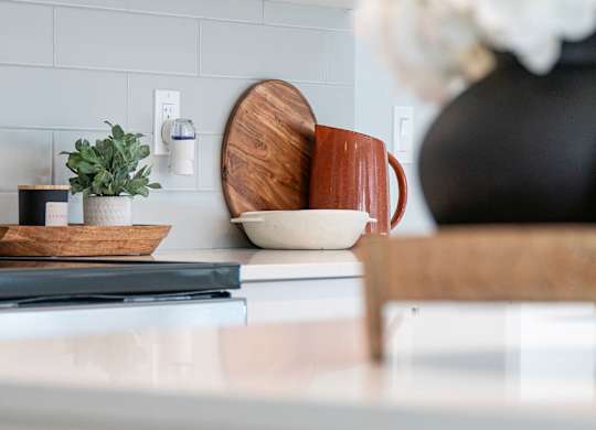 A kitchen counter with a microwave, a plant, and a vase with flowers.