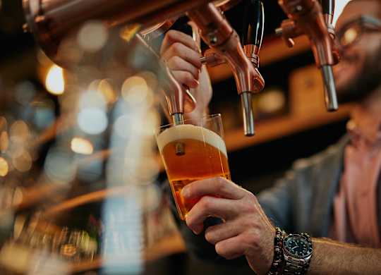 A man is pouring a beer from a tap into a glass.