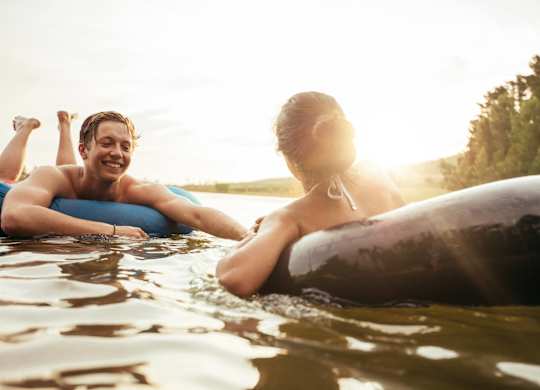 Two people are floating on a surfboard in the water.