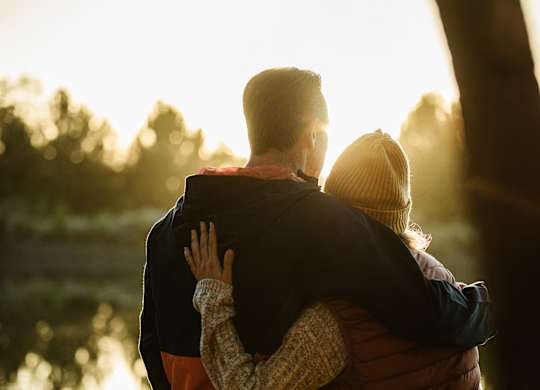 A couple is hugging each other in a sunny outdoor setting.