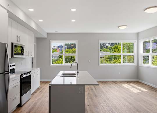 A modern kitchen with a refrigerator, oven, and sink.