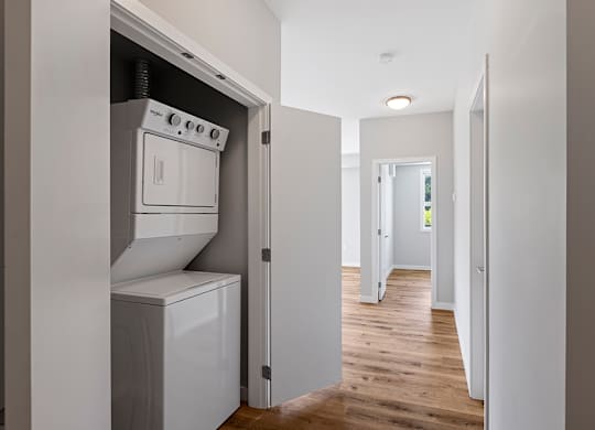 A white oven and dishwasher are built into a wall in a narrow hallway.