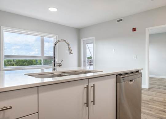 A kitchen with a stainless steel sink and white cabinets.