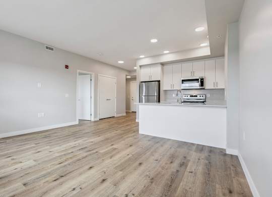 A kitchen with white cabinets and a wooden floor.