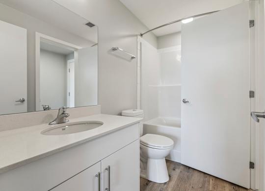 A white bathroom with a sink, toilet, and shower.