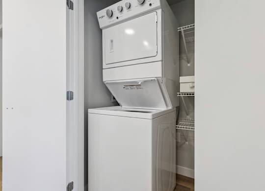 A white dishwasher is stacked on top of a white oven.