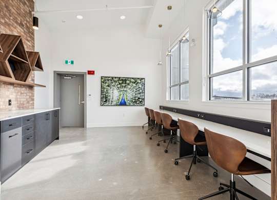 A room with a long table and chairs with a view of the outside.