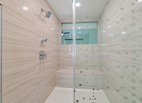 A bathroom with a glass shower stall and a glass door.