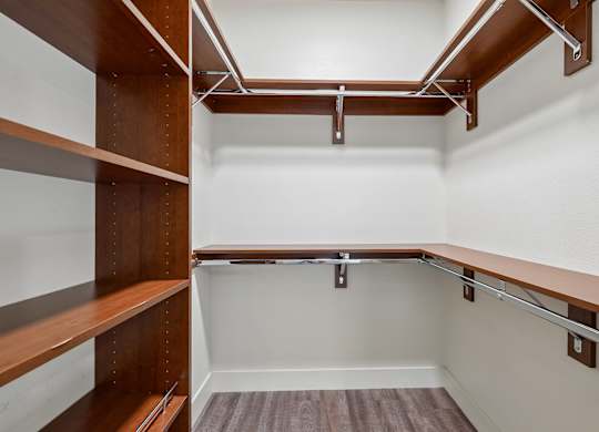 A walk-in closet with shelves and a wooden floor.