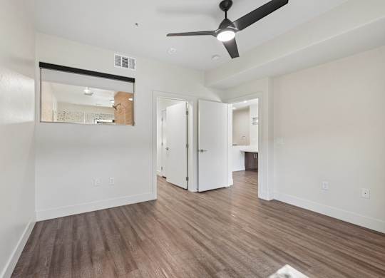 A room with a ceiling fan and wooden flooring.