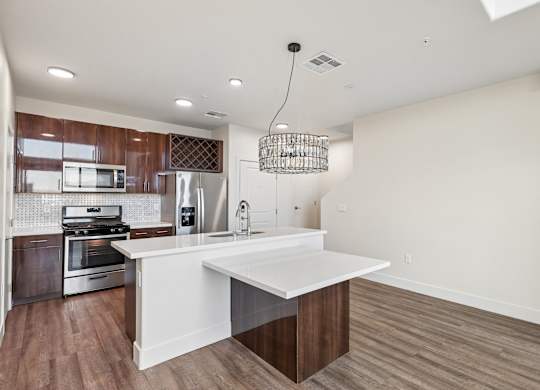 A modern kitchen with a white island and wooden floors.