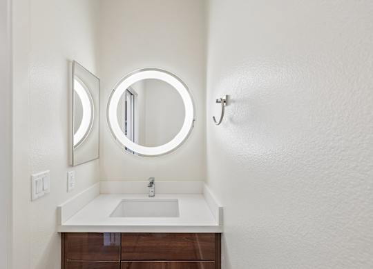 A bathroom with a round mirror and a sink.