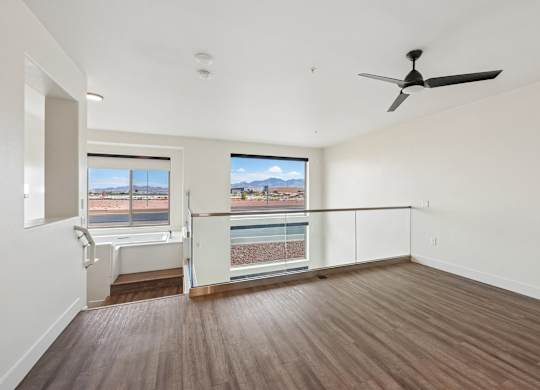 A room with a ceiling fan and a view of a pool and mountains through the window.