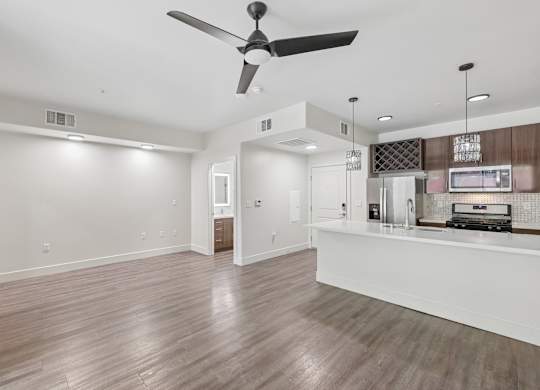 A spacious living room with a ceiling fan and hardwood flooring.