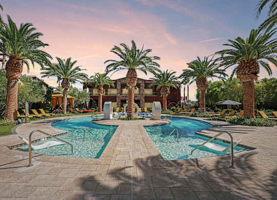 A pool surrounded by palm trees and lounge chairs.