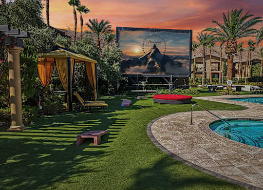 A movie screen in a backyard with a pool.