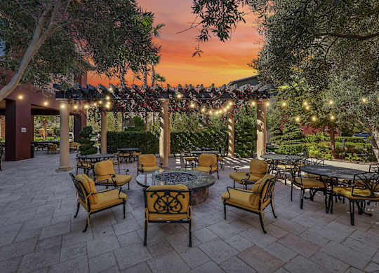 A patio with tables and chairs is set up under a canopy with lights strung up.