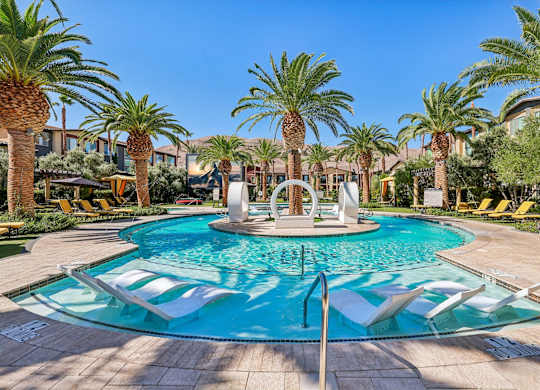 A pool surrounded by palm trees and a fountain in the middle.