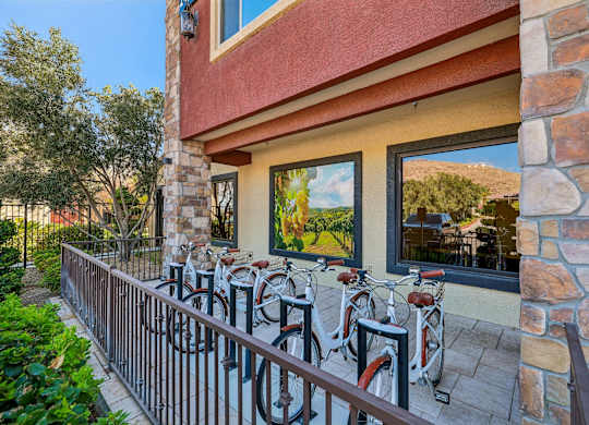 A row of bicycles are parked on a balcony.