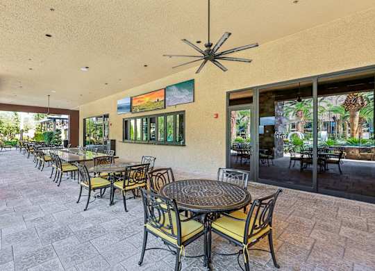 A patio with tables and chairs and a ceiling fan.