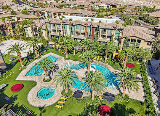 A pool surrounded by palm trees and umbrellas.