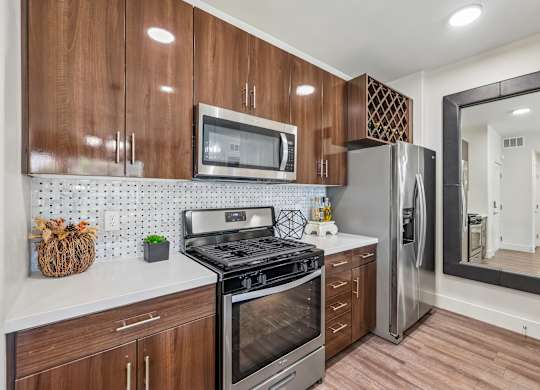 A kitchen with wooden cabinets and a stainless steel refrigerator.