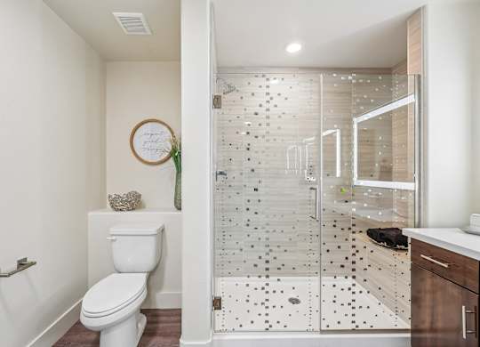 A white toilet sits in a bathroom with a glass shower stall.