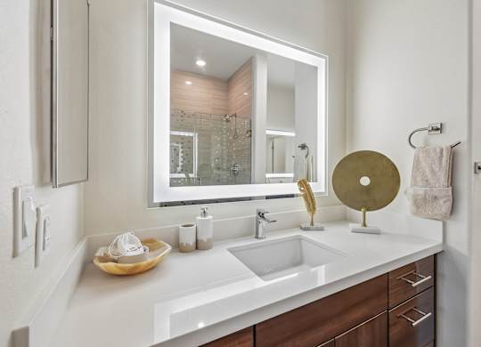 A bathroom with a white counter top and a round mirror.