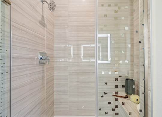 A shower with a glass door and a green bag on the floor.