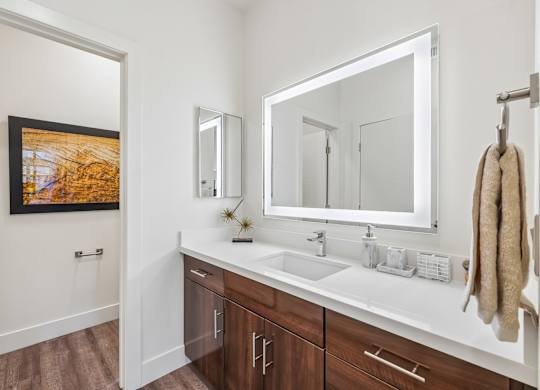 A bathroom with a white sink and brown cabinets.