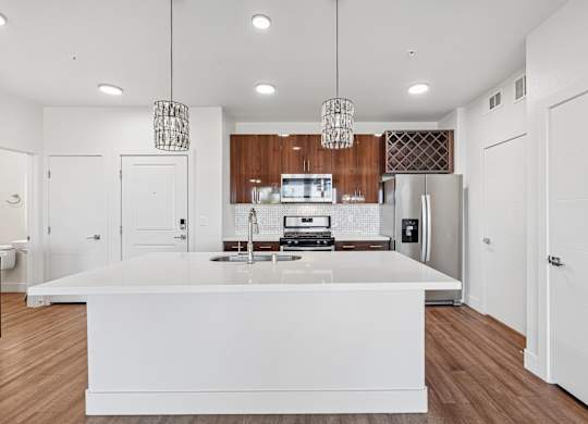 A modern kitchen with a white island and wooden cabinets.