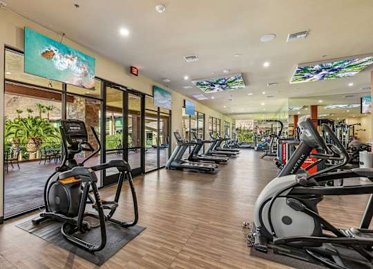 A gym with treadmills, elliptical machines, and other exercise equipment.