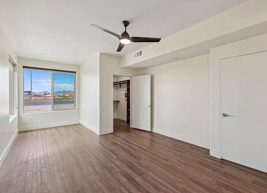 A room with a ceiling fan and wooden flooring.