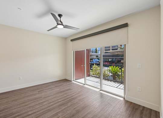 A room with a ceiling fan and sliding glass doors.