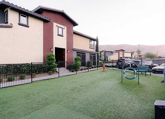 A playground with a green swing set in the middle of a grassy area.