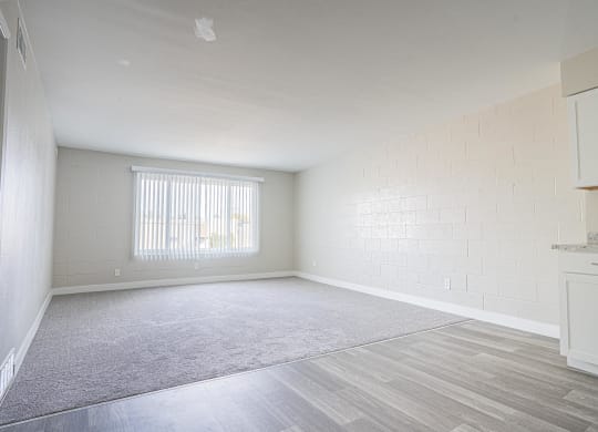an empty living room with a window and a kitchen at Regency Park, Nevada