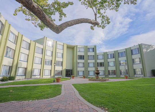 a courtyard in front of an apartment building with green grass and a tree at Regency Park, Reno, 89509