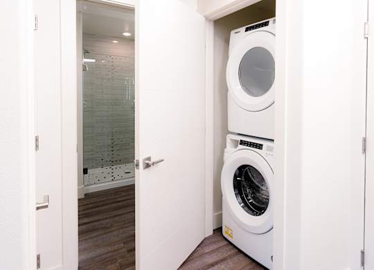 A white washing machine is in a small white closet.