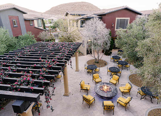 A patio with yellow chairs and a fire pit.