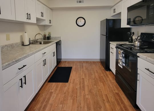 a kitchen with white cabinets and black appliances at Monroeville Apartments, Monroeville