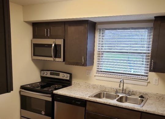 an empty kitchen with granite countertops and stainless steel appliances at Monroeville Apartments, Monroeville, PA