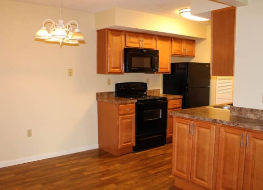 a kitchen with wooden cabinets and black appliances at Monroeville Apartments, Monroeville, PA, 15146