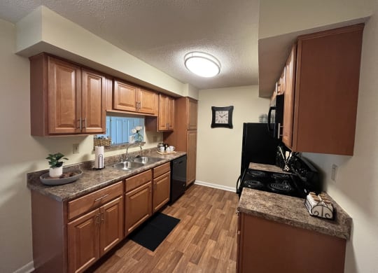 a kitchen with brown cabinets and a black stove top oven at Monroeville Apartments, Monroeville, PA, 15146