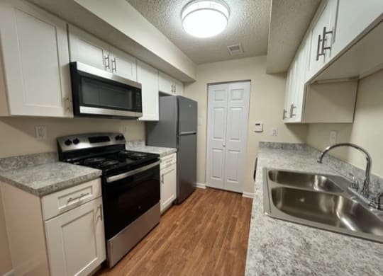 a kitchen with a stove a sink and a microwave at Monroeville Apartments, Monroeville, Pennslyvania