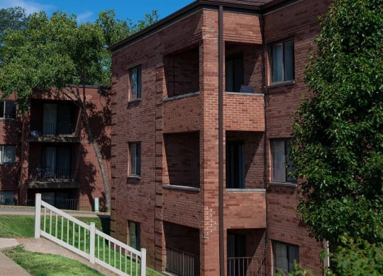 a red brick building with a white fence in front of it at Monroeville Apartments, Pennslyvania